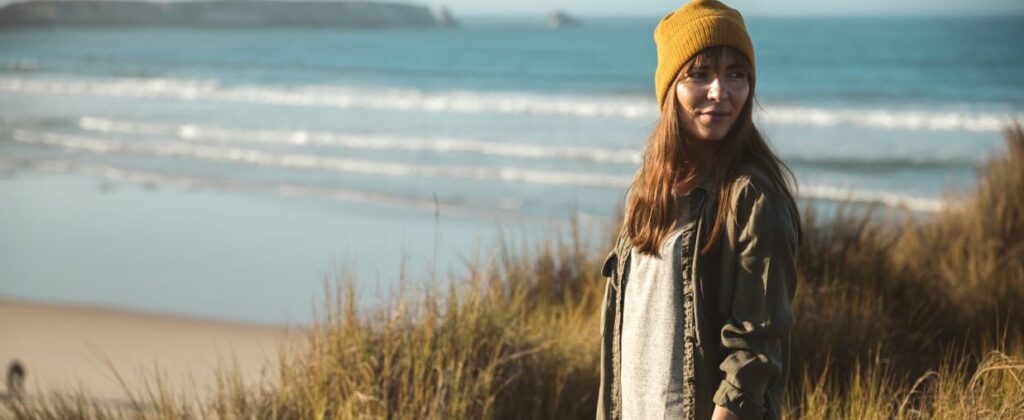Frau mit Mütze am Meer dreht sich um Umschulung