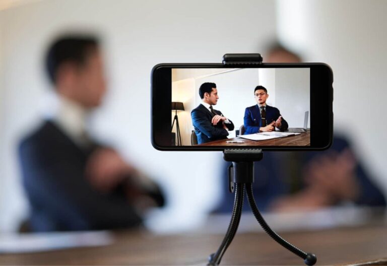 Corporate Influencer , zwei Geschäftsleute in Anzügen die ihr Gespräch mit dem Smartphone aufzeichnen