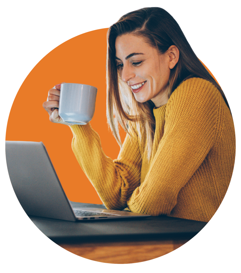 Frau mit gelbem Pulli und Kaffeetasse vor Laptop