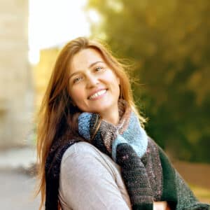 Portrait einer lächelnden Frau mit langen brauen Haaren.