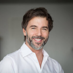 Portrait eines Mannes in einem weißem Hemd.