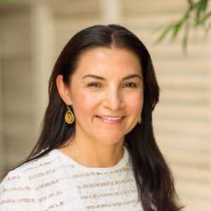 Frau mit langen dunkelbraunen Haaren und weißem Shirt.