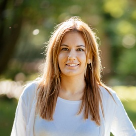 Lächelnde junge Frau mit langen hellbrauen Haaren.