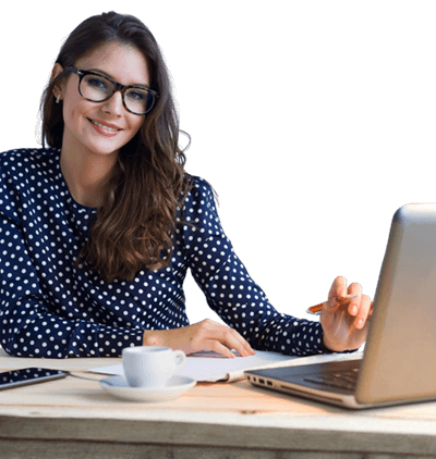 Frau in dunkelblauer Bluse sitzt an einem Schreibtisch mit geöffnetem Laptop vor sich.