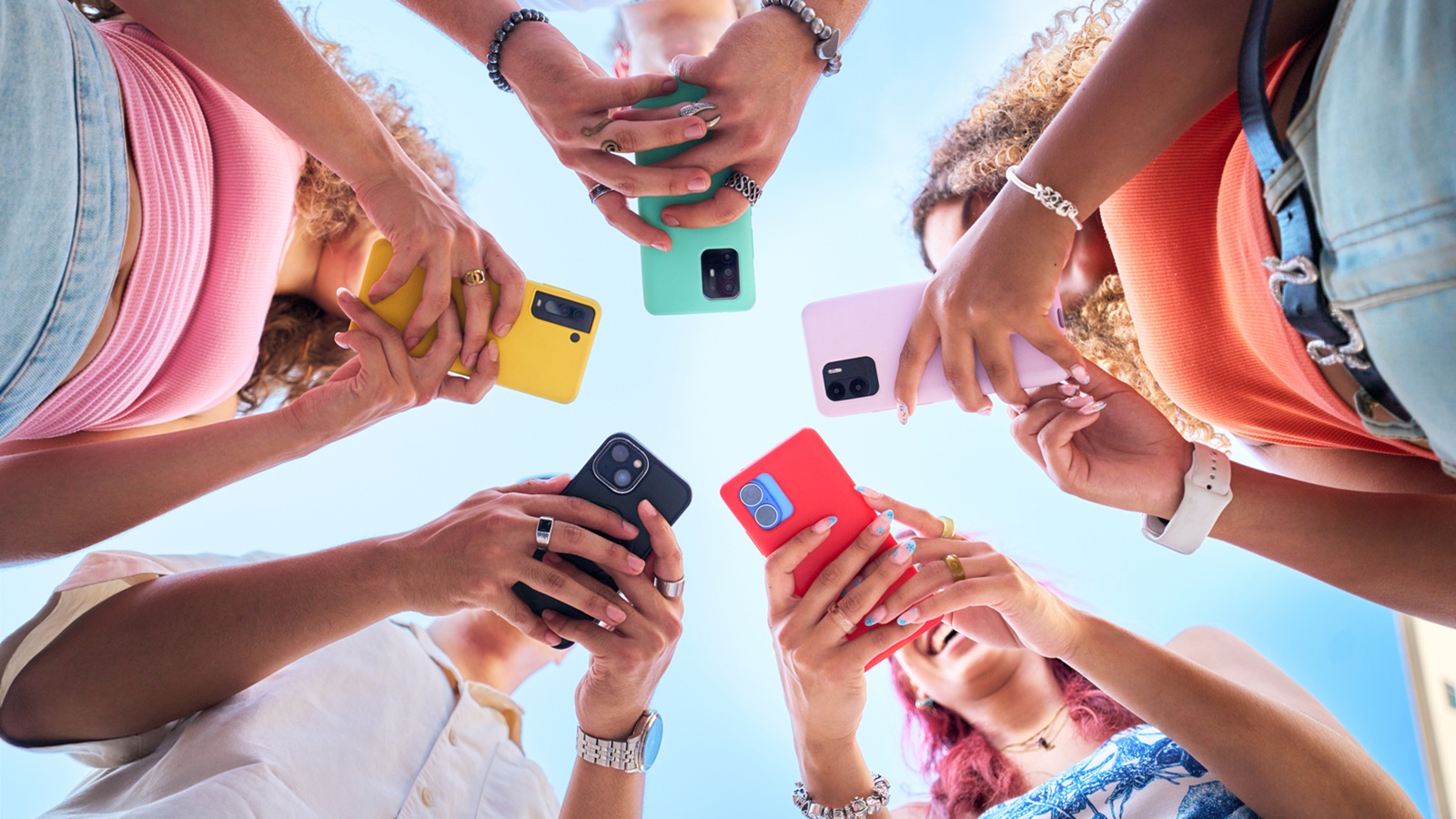 fünf Personen, die in einer Gruppe zusammenstehen, und ihre Smartphones nutzen