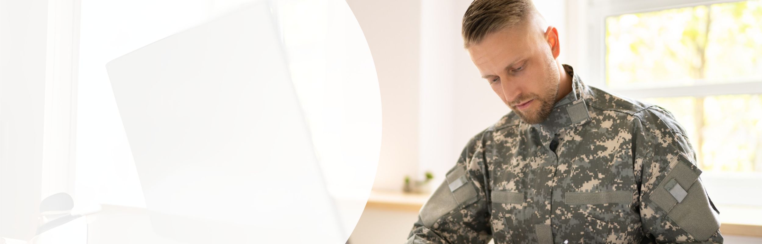 Ein Mann in Bundeswehr-Dienstkleidung sitzt an einem Schreibtisch.