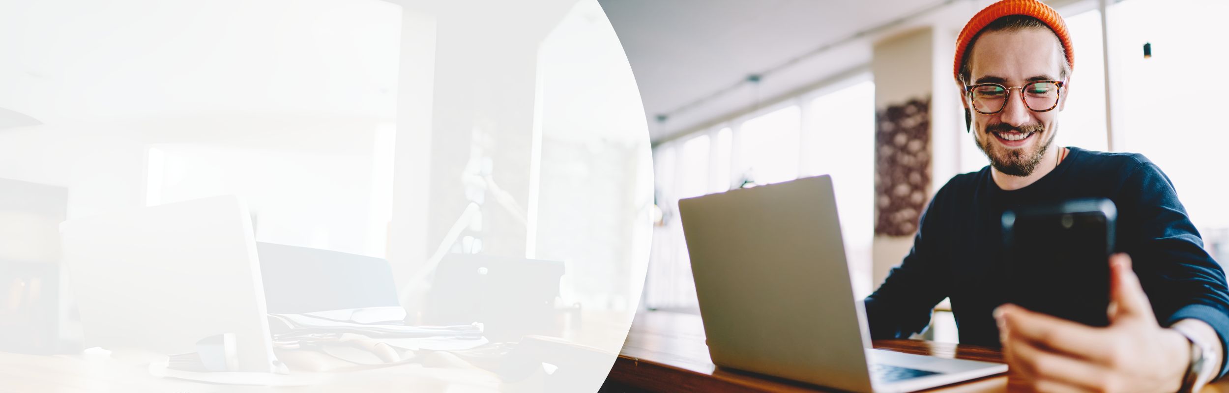 Mann mit orangener Mütze und Brille blickt auf das Smartphone in seiner Hand.