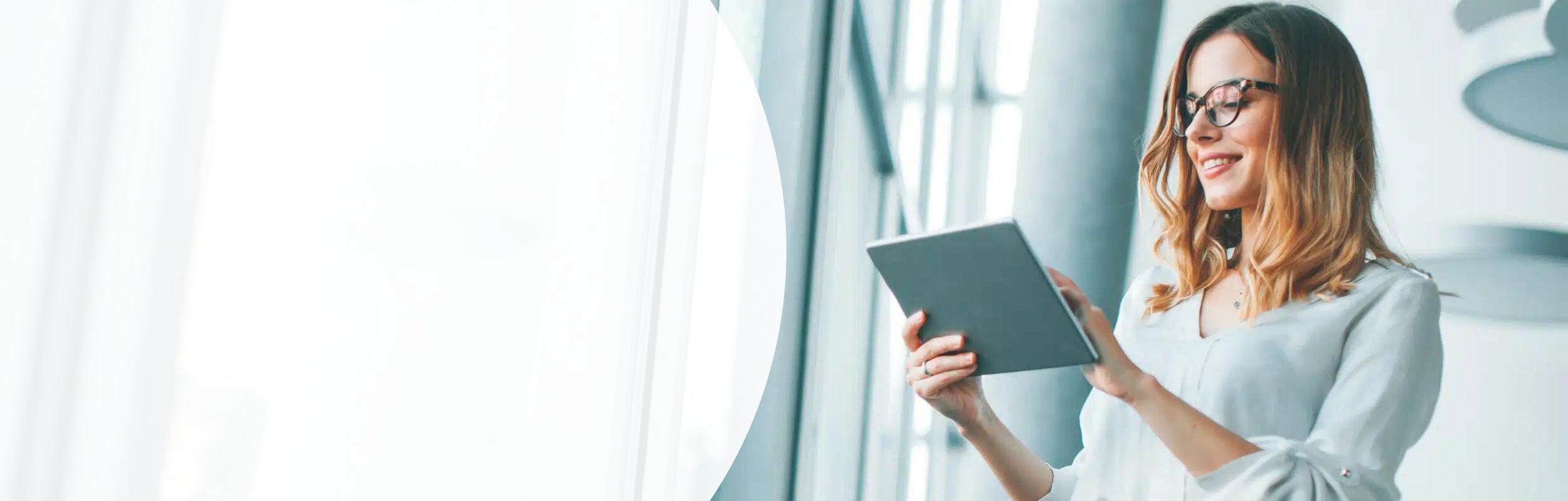 Lächelnde Frau sieht auf das Tablet, das sie in den Händen hält.