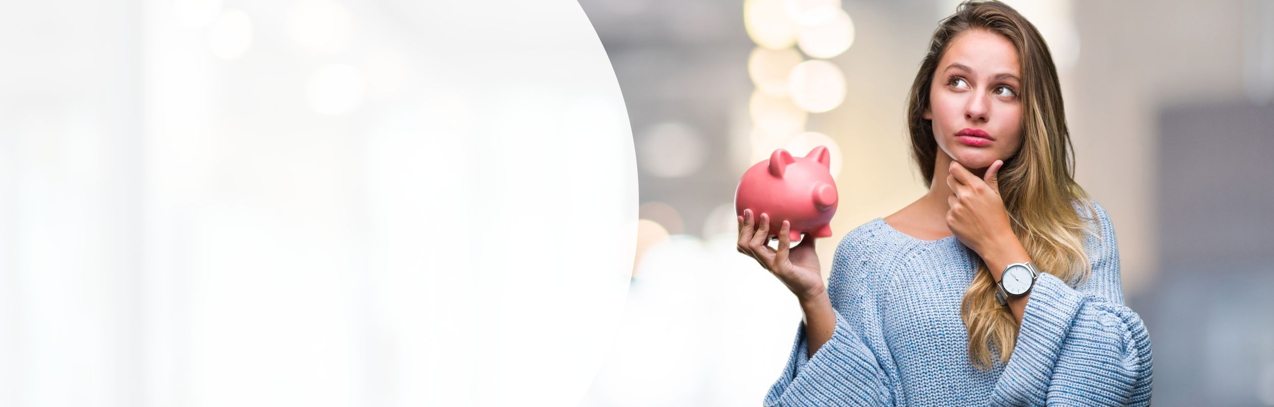 Frau in einem blauen Pullover mit nachdenklichem Gesichtsausdruck hält ein Sparschwein in der Hand.