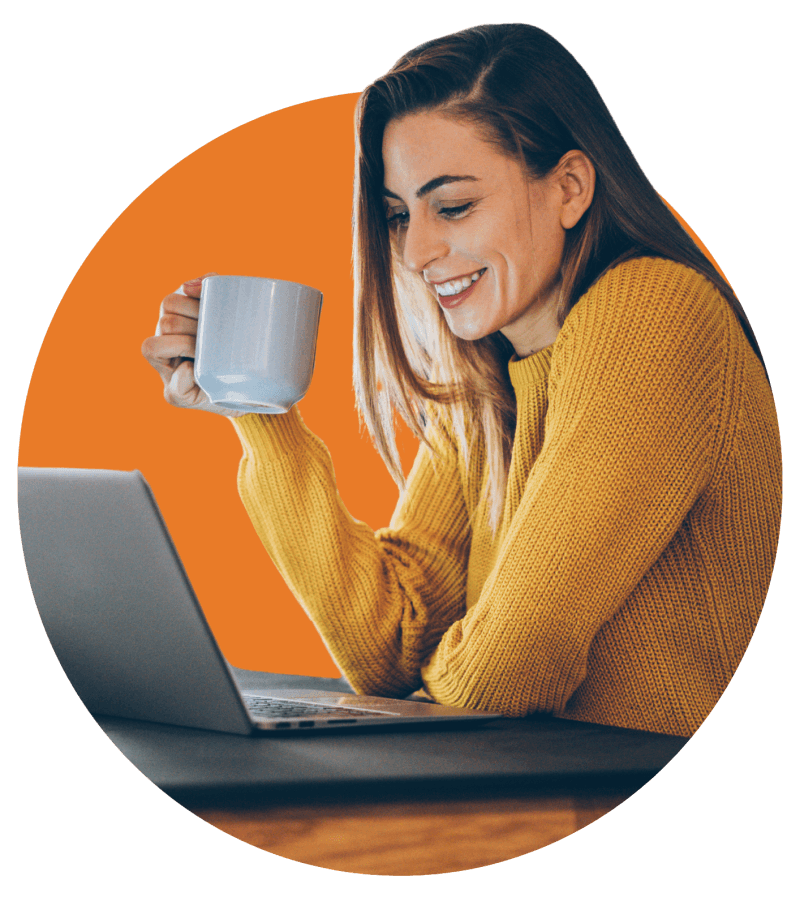 Frau mit gelbem Pulli und Kaffeetasse vor Laptop